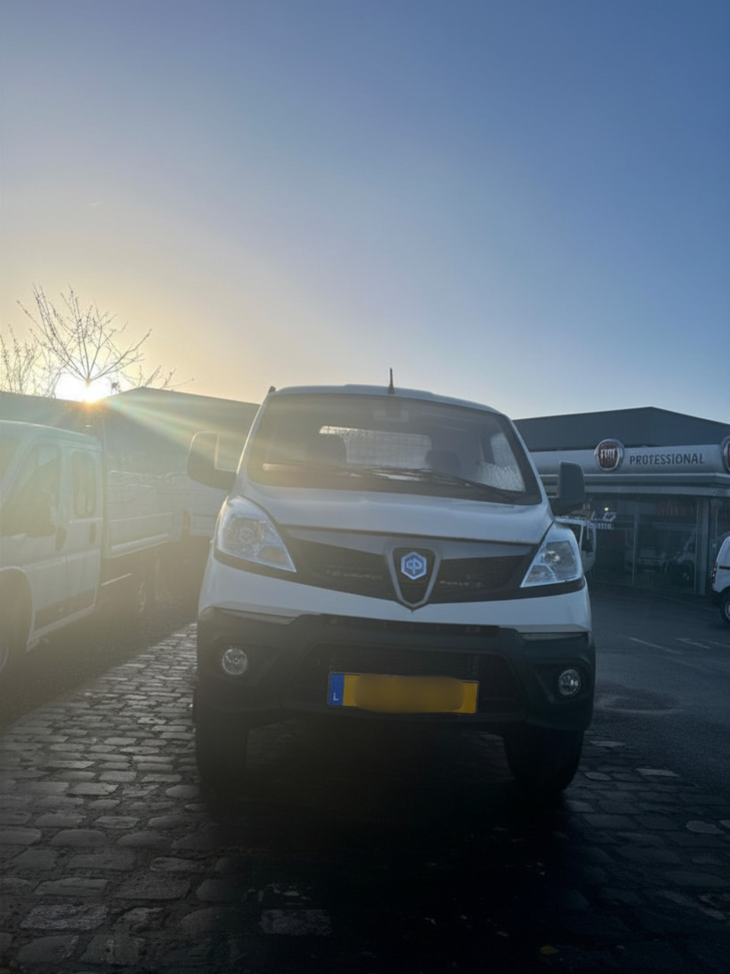 Camionnette blanche stationnée sur pavés au crépuscule