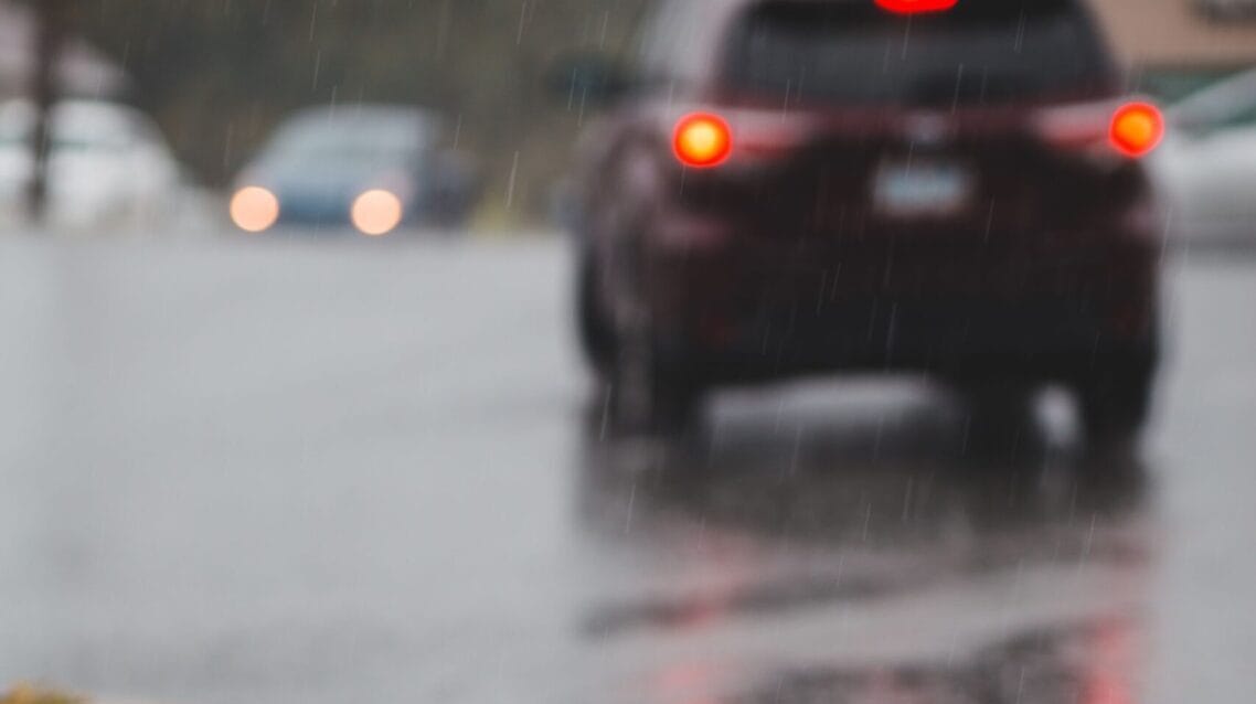 Feux arrière de voiture reflétés sur route mouillée sous la pluie