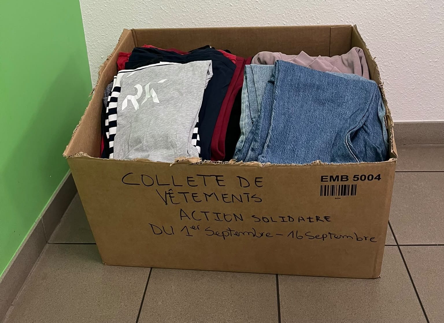 Carton de collecte solidaire rempli de vêtements pliés