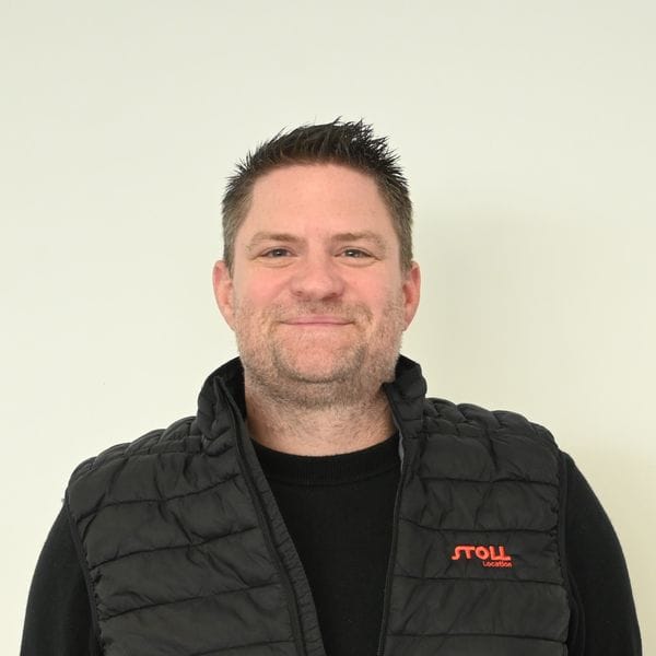 Homme souriant en veste noire devant fond clair