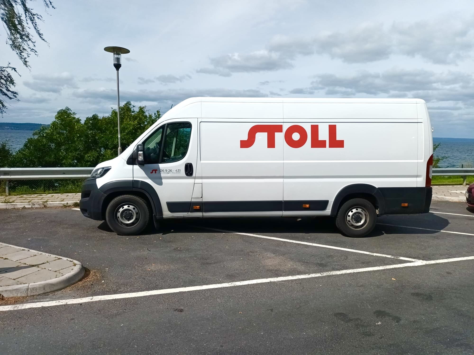 Un fourgon blanc floqué Stoll Location sur un parking