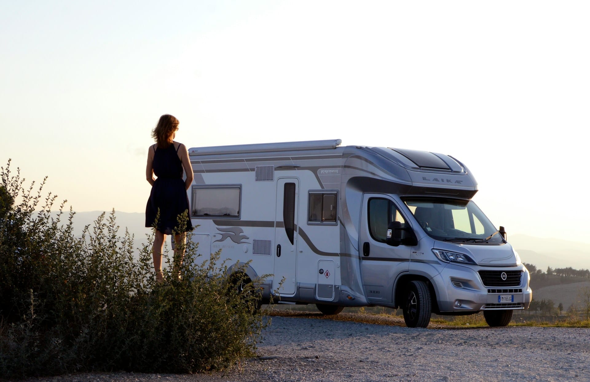 Femme contemplant un camping-car au coucher du soleil