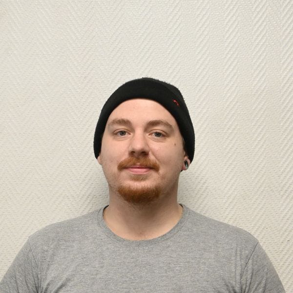 Personne portant bonnet noir et t-shirt gris souriant.