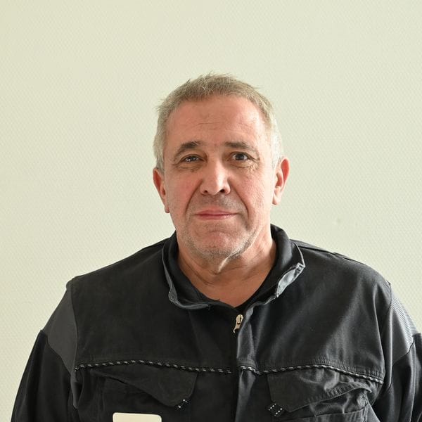 Homme en tenue de travail devant un mur clair