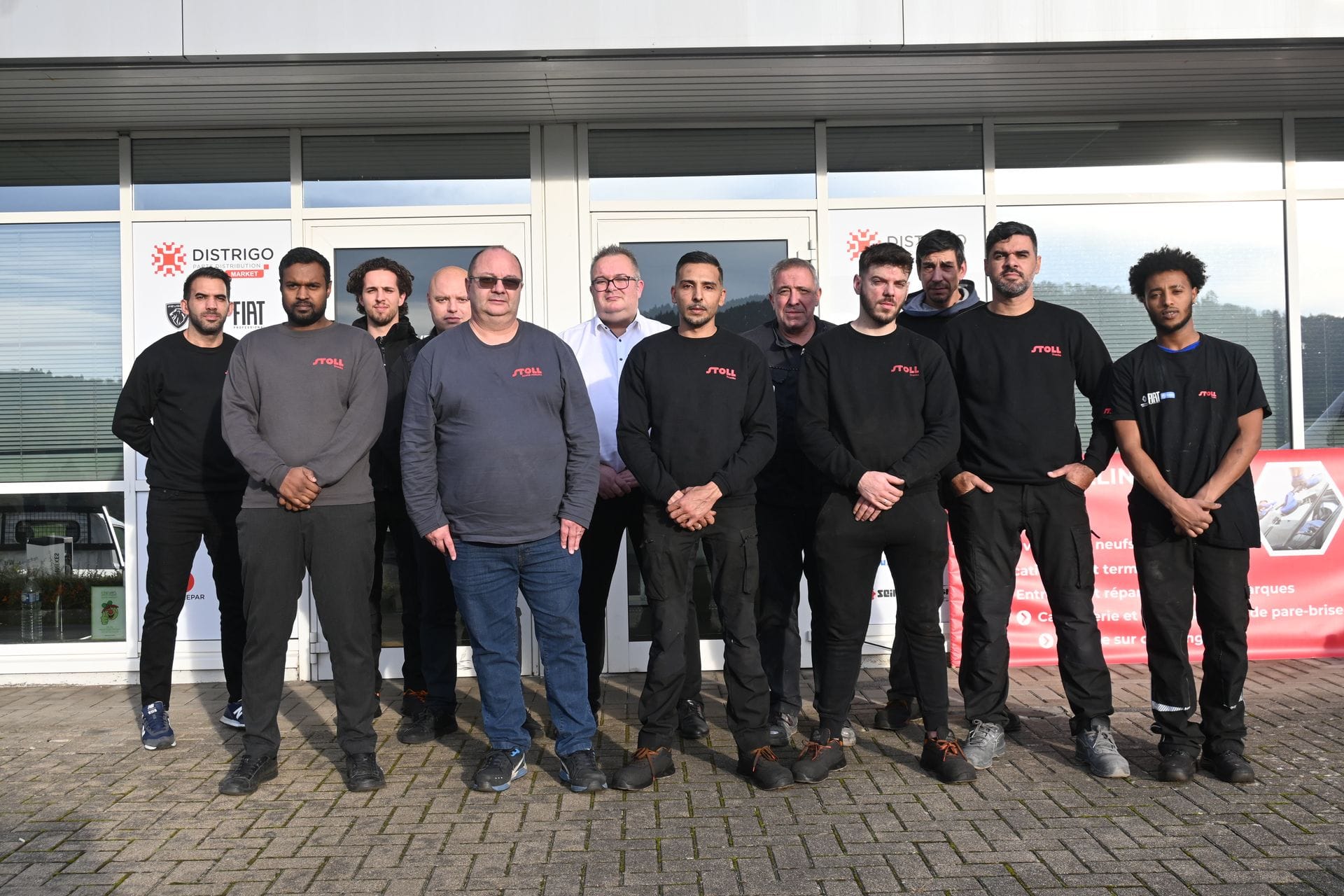 Équipe d’atelier posant devant un bâtiment industriel