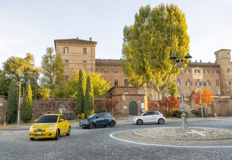 Trois véhicules en situation de consommation - jaune, bleu et blanc avec une grande maison en arrière plan