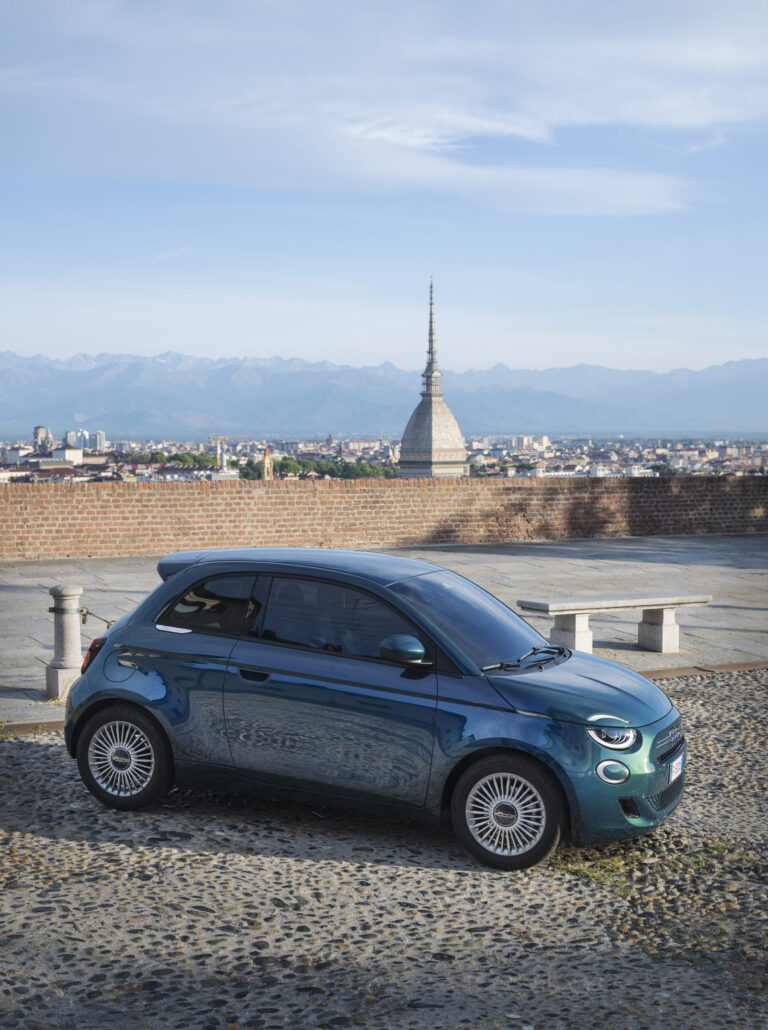 Une voiture de couleur ocean green placée en bordure de mer
