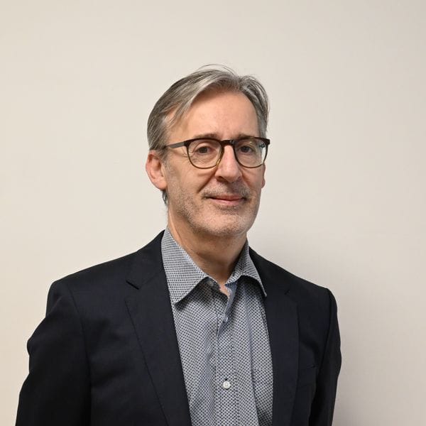 Homme en costume portant des lunettes souriant légèrement