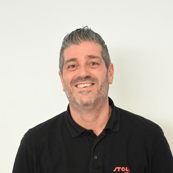 Homme souriant en polo noir sur fond clair