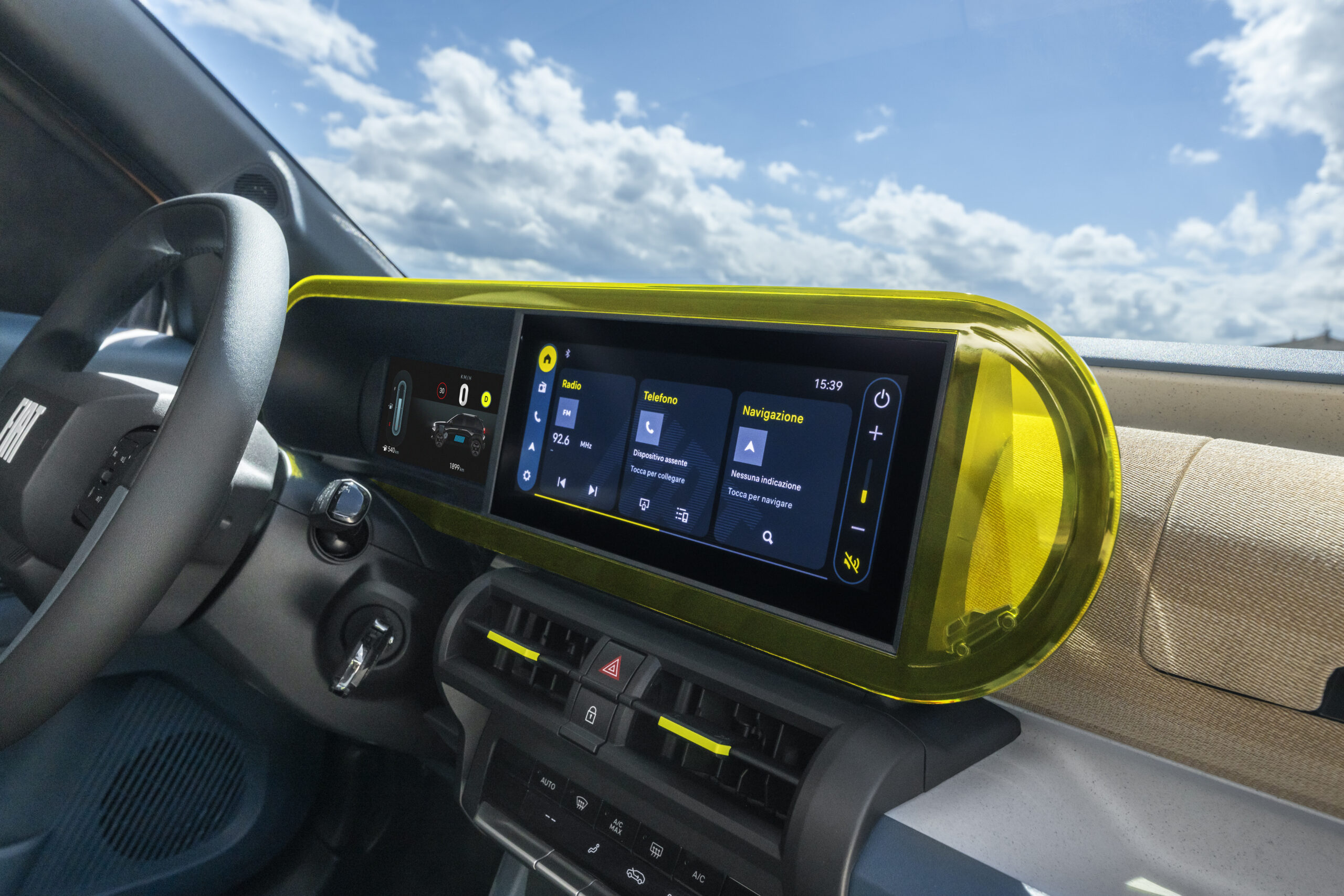 Tableau de bord d’une voiture moderne avec écran tactile multimédia central et entourage jaune translucide, affichant radio, téléphone et navigation.