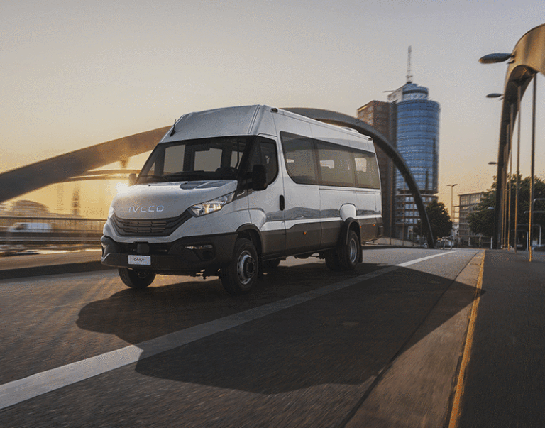 Minibus gris traversant un pont urbain au coucher du soleil