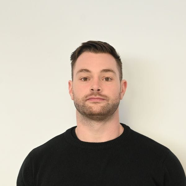 Homme en pull noir devant fond clair