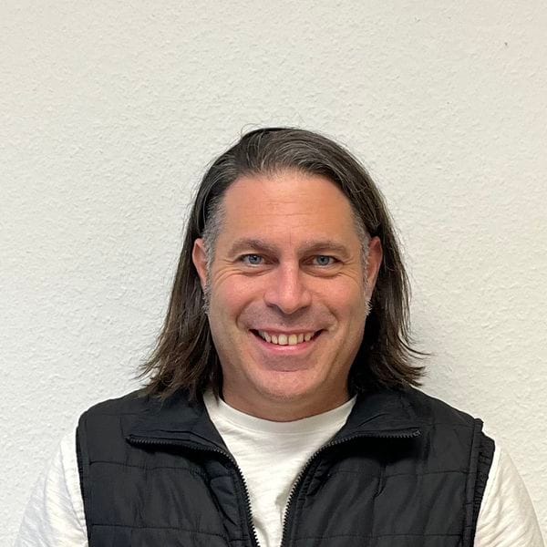 Homme souriant devant un mur blanc