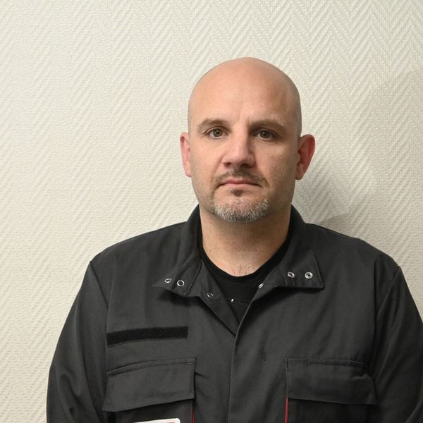 Homme en tenue de travail devant un mur clair