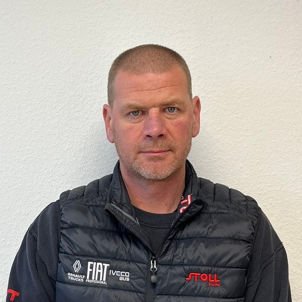 Homme portant une veste noire devant un mur blanc