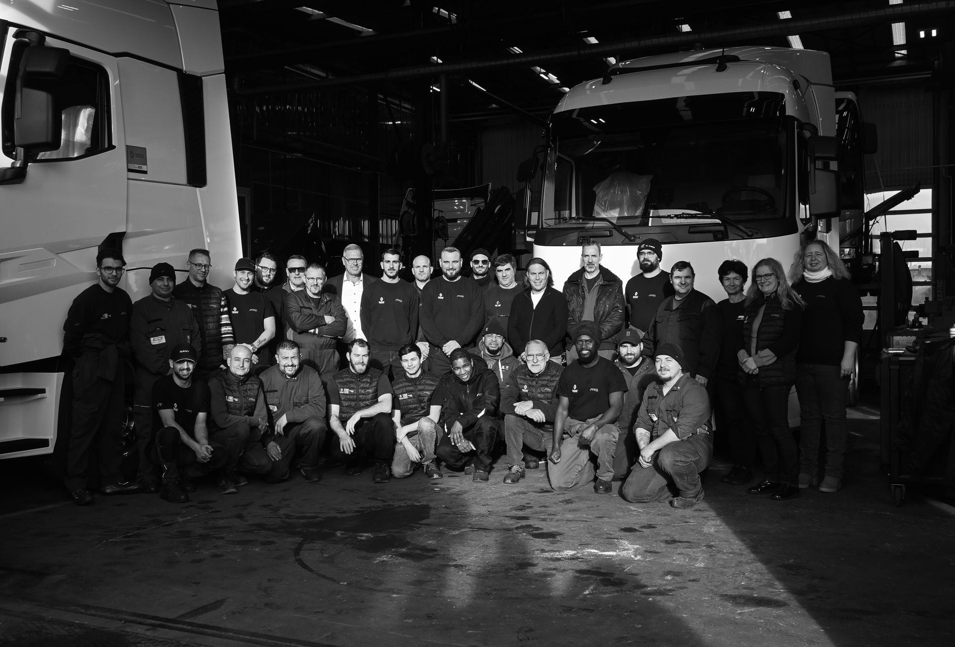 Équipe d’atelier posant devant des poids lourds.