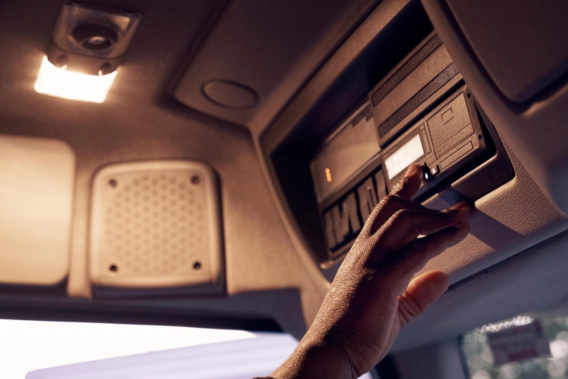 Une main appuie sur un bouton d'un tachygraphe dans un camion.