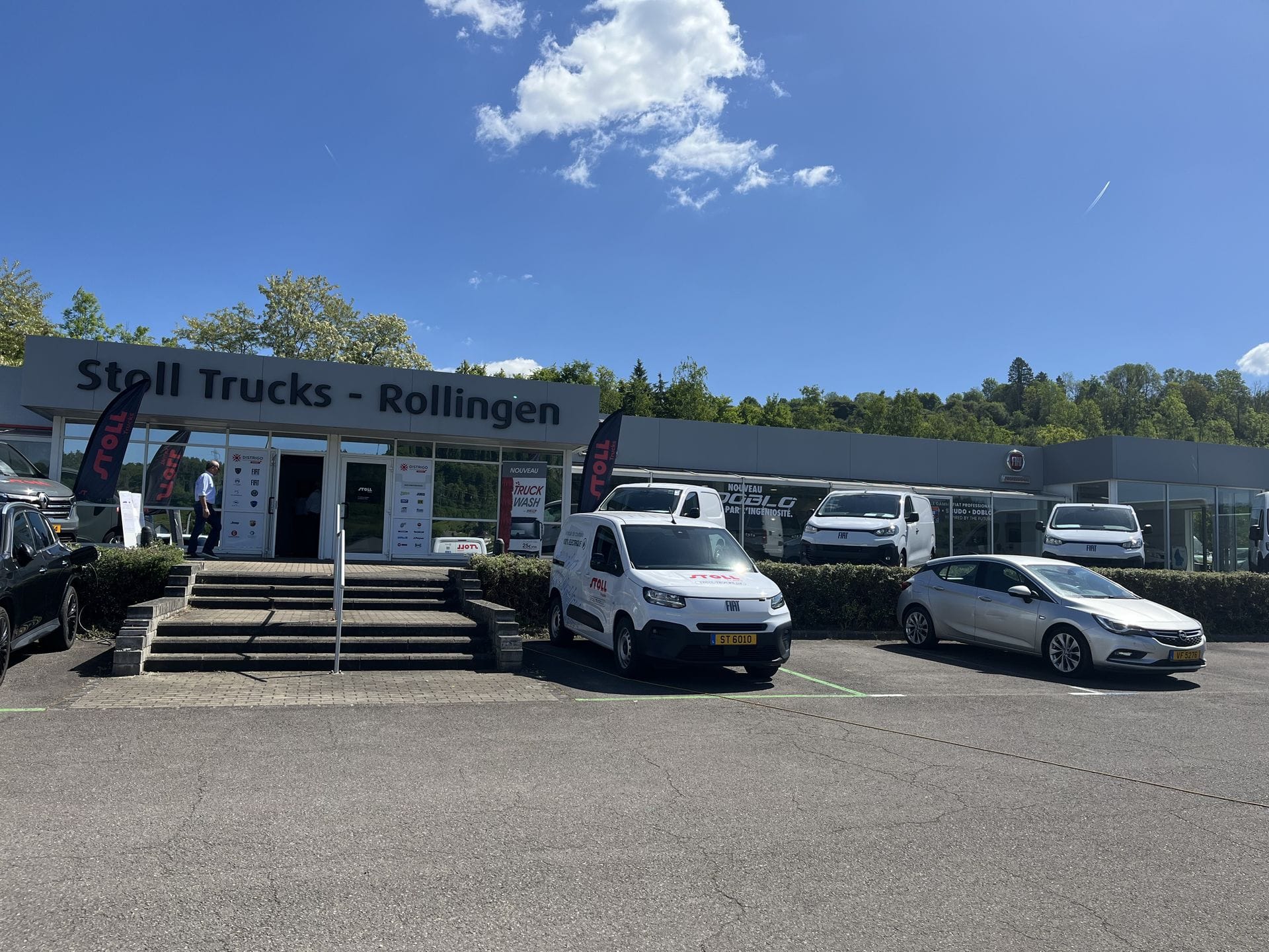 Photo extérieur de l'entrée de Stoll Trucks Rollingen. On voit quelques utilitaires garés sur le parking.