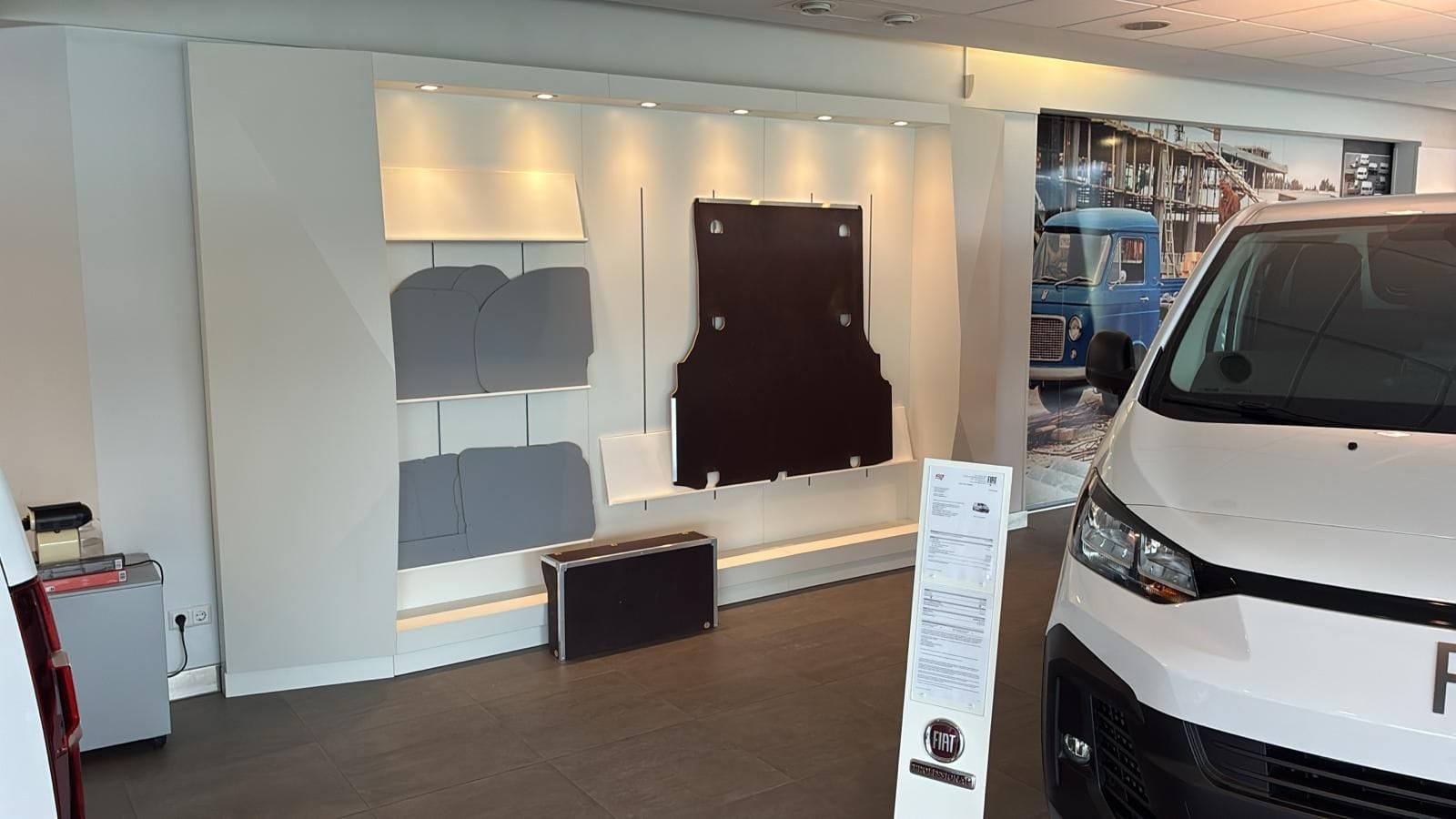 Photo d'iIntérieur avec un utilitaire Fiat blanc en premier plan, et des pièces utilitaire sur le mur du fond.