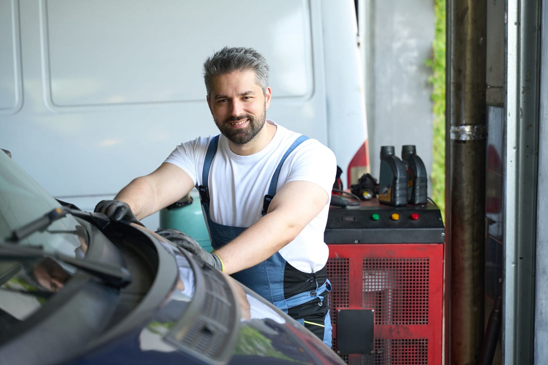 Mécanicien souriant réparant une voiture dans un garage