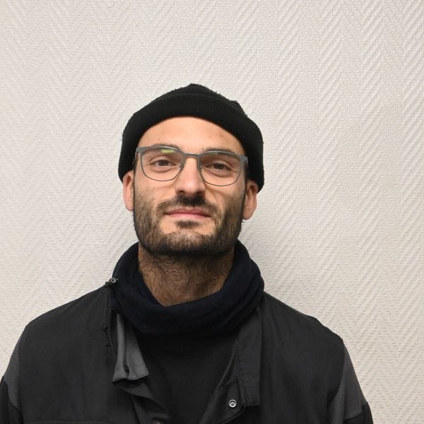 Homme portant lunettes, bonnet noir et écharpe sombre